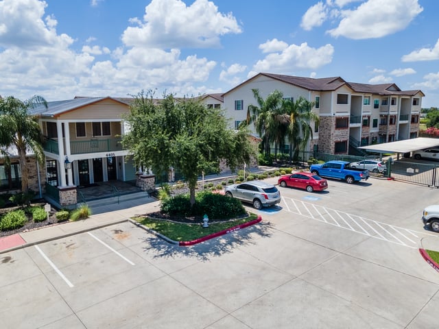 Multifamily apartment building exterior with parking lot and entrance.