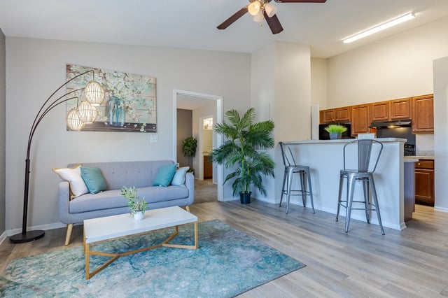 Living room with sofa, coffee table, and kitchen bar with stools.