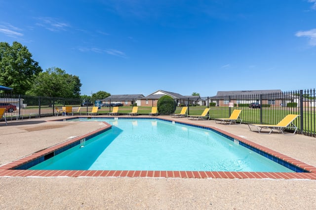 Outdoor swimming pool with lounge chairs and blue sky.