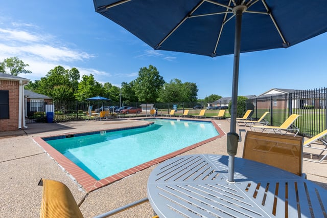 Outdoor swimming pool area with lounge chairs and umbrellas.