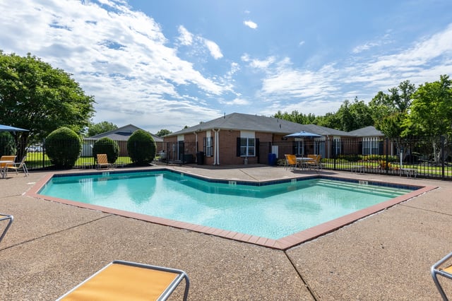 Swimming pool with lounge chairs and umbrellas at a multifamily property.