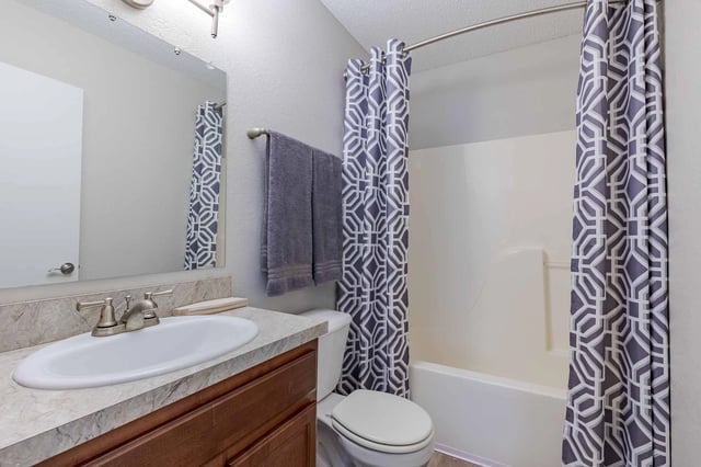 Bathroom with sink, toilet, and shower with gray patterned curtains.