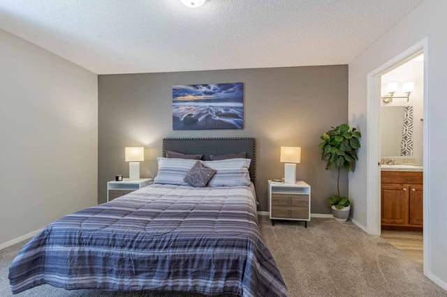 Bedroom with a king-size bed, nightstands, and a view of the bathroom.