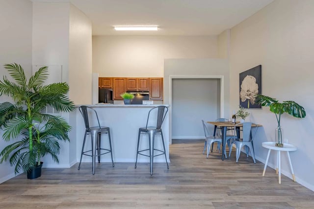 Kitchen island with bar stools and adjacent dining area with a table and chairs.