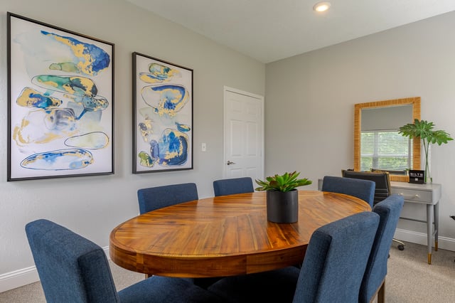 Elegant dining area with a large wooden table and blue chairs, decorated with abstract art.