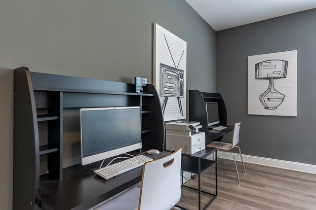 Community business center with workstations, computers, printer, and decorative wall art.