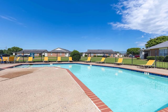 Community pool with lounge chairs and a fenced enclosure.