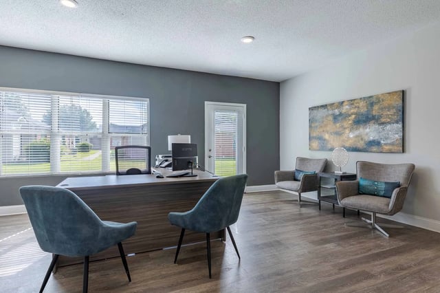 Modern leasing office reception area with a large desk, comfortable seating, and artwork.