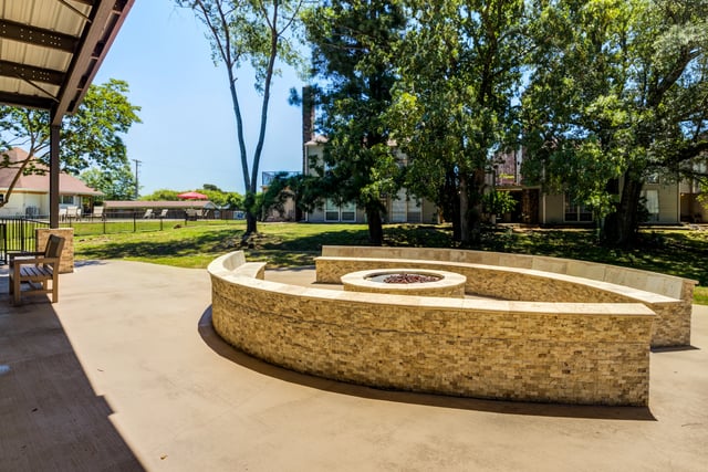 Outdoor fire pit with curved seating area and trees