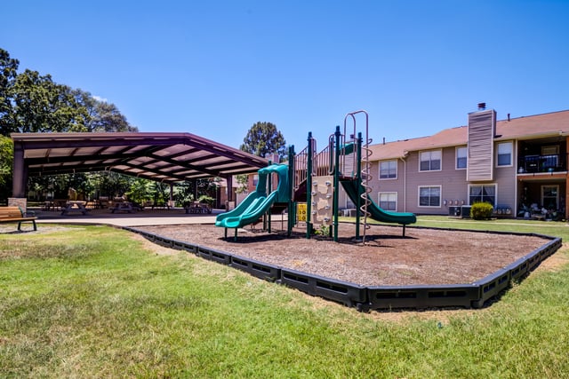 Playground with slides and swings next to a covered picnic area.