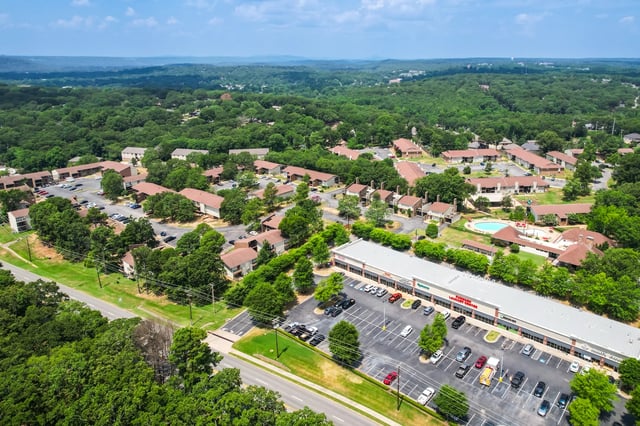 Aerial view of apartment complex with a pool and surrounding buildings.