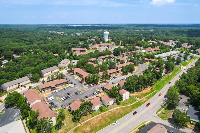 Aerial view of apartment buildings surrounded by trees and a road.