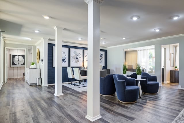 Modern lounge area with navy blue accent chairs and abstract art.