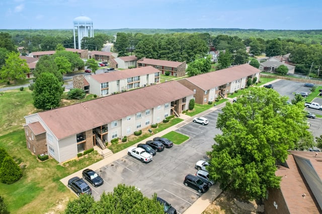Aerial view of apartment buildings with parking lots and trees.