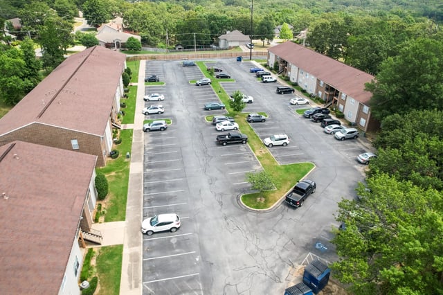 Aerial view of apartment buildings with a large parking lot filled with cars.
