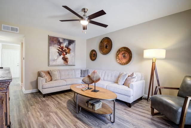Modern living room with sectional sofa, coffee table, floor lamp, and abstract art.