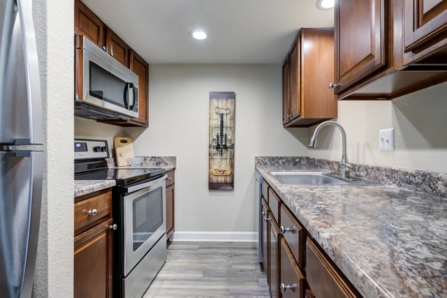 Kitchen with stainless steel appliances, granite countertops, and dark wood cabinets.