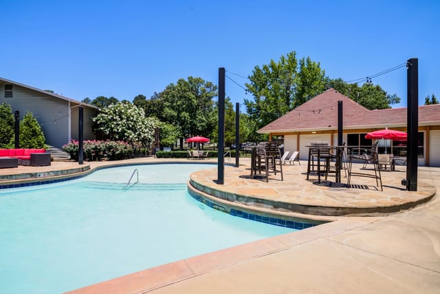 Resort-style outdoor swimming pool with a curved design and a separate seating area with tables and chairs.