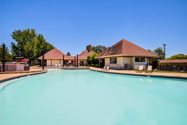 Sparkling outdoor swimming pool with lounge chairs and a poolside building.