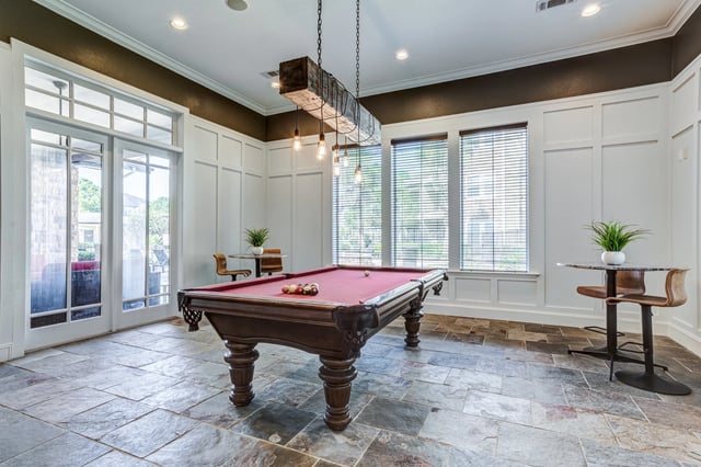 Billiard table in a community lounge with tables and chairs.