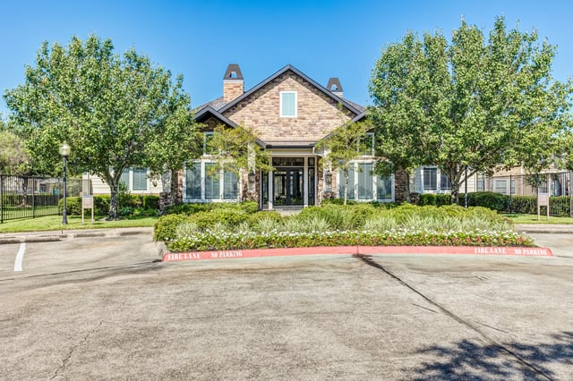 Exterior building entrance with stone facade, large windows, and landscaping.