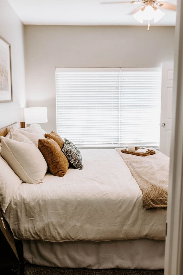 Cozy bedroom with a king-size bed and white linens, accented by decorative pillows and a ceiling fan.
