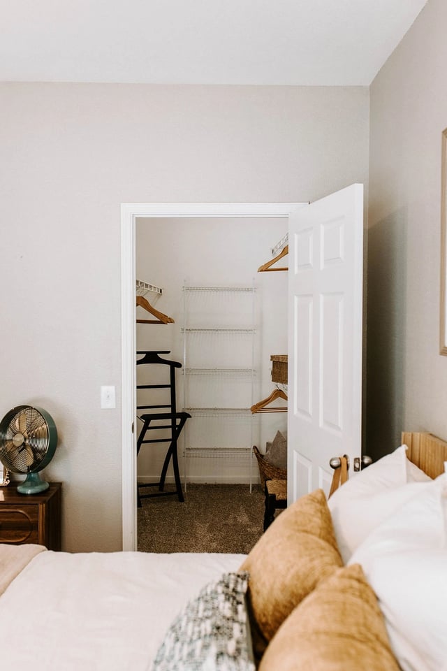 Bedroom with open closet and vintage fan.