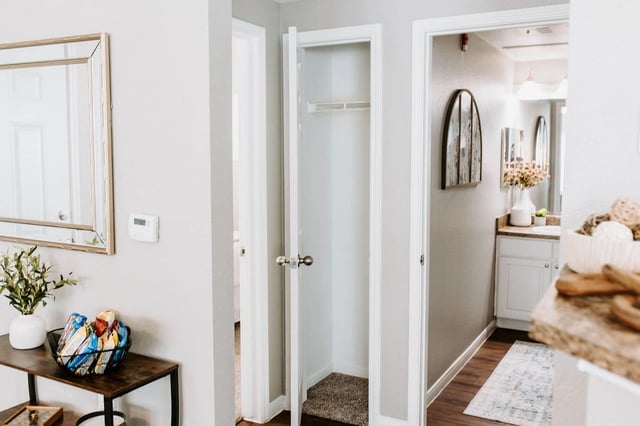 Hallway with a mirrored accent cabinet and a linen closet.