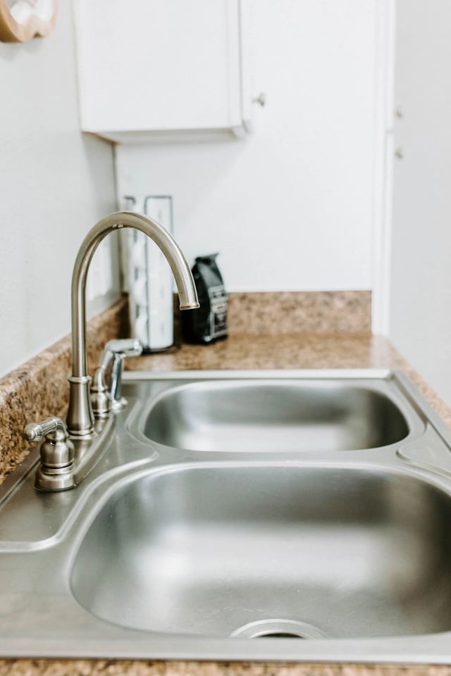Double kitchen sink with chrome faucet and granite-patterned countertop.