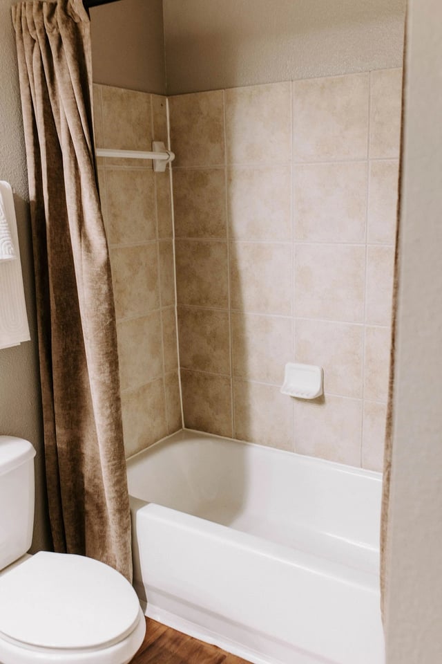 Bathroom with bathtub, shower curtain, and toilet.