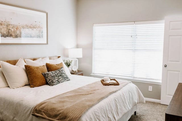 Bedroom with a large bed, nightstand, and a window with blinds.