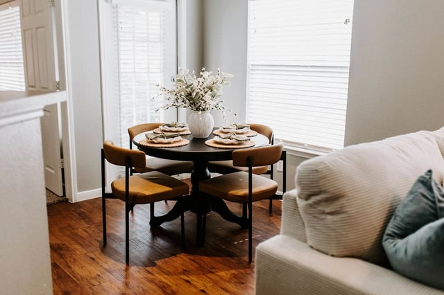 A dining table with four chairs and place settings is shown.