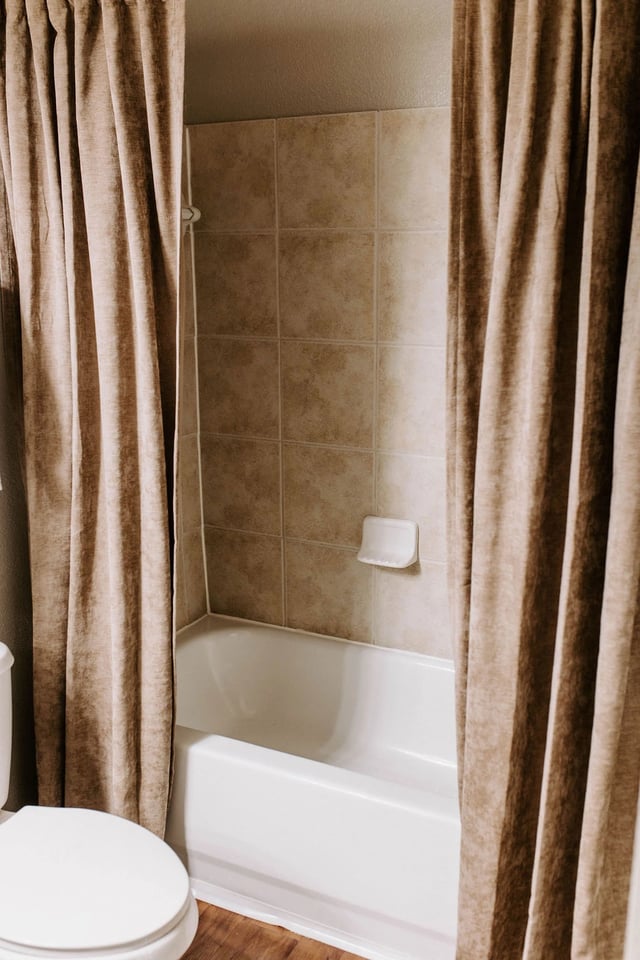 Bathroom with a bathtub, shower curtain, and toilet.