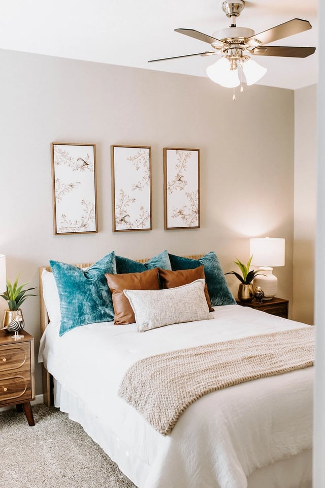 Bedroom with a queen bed, teal and brown pillows, and abstract bird art.