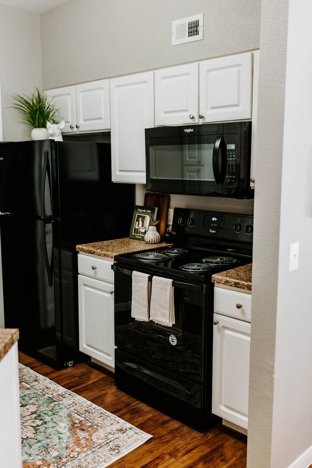 Modern kitchen with black appliances, white cabinets, and granite countertops.