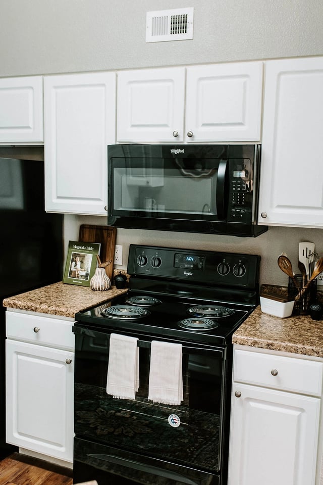 Black Whirlpool stove with microwave above and white cabinetry.