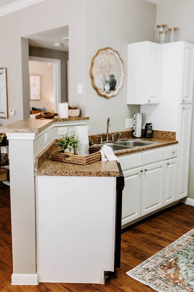 Kitchen area with granite countertops, white cabinets, stainless steel sink, and pendant light.