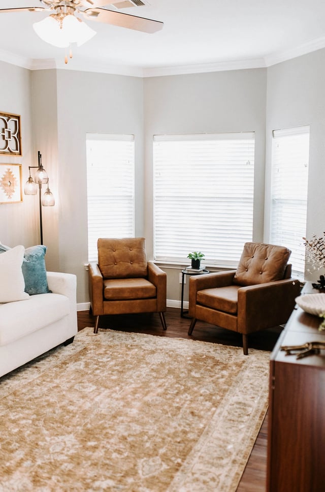 Living room with two brown leather armchairs and a white sofa.