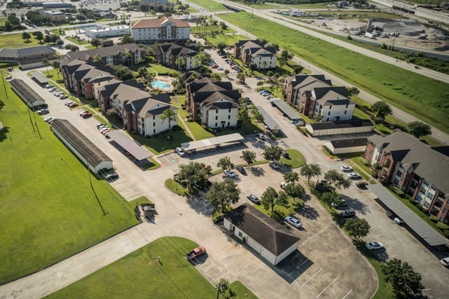 Aerial view of apartment complex with buildings, parking, and amenities.