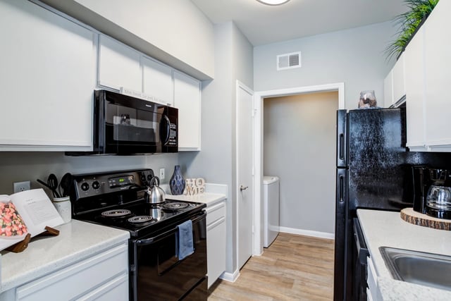 Modern kitchen with black appliances and white cabinetry.
