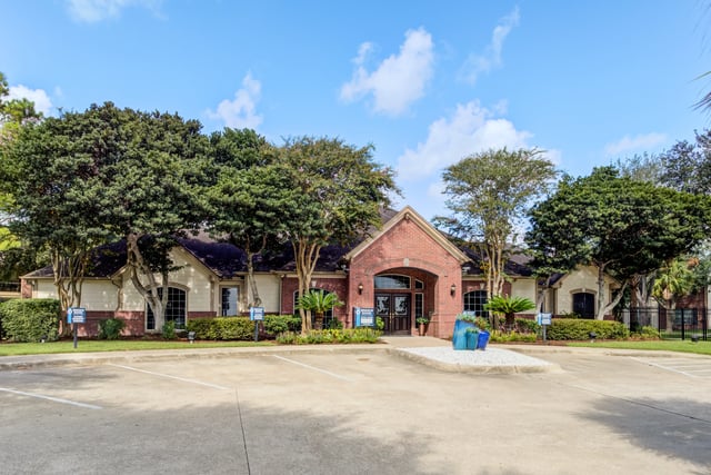 Brick building with arched entryway and manicured landscaping.