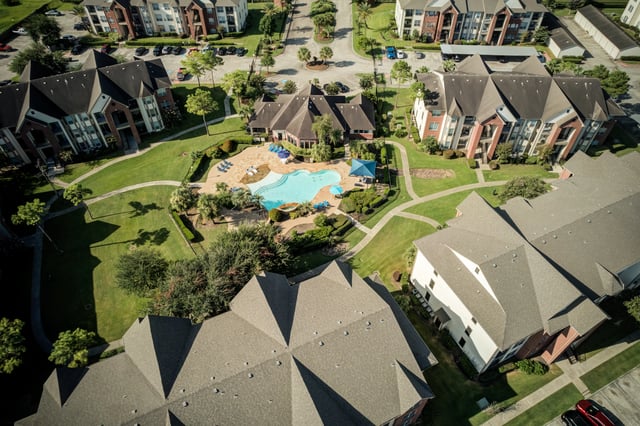 Aerial view of apartment complex amenities including a large swimming pool and surrounding buildings.