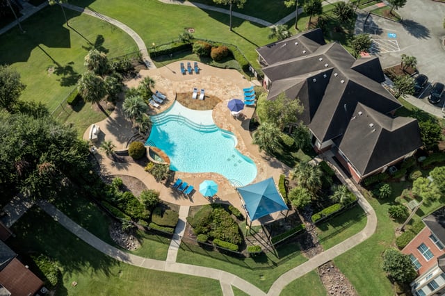 Aerial view of a resort-style swimming pool with lounge chairs and umbrellas.