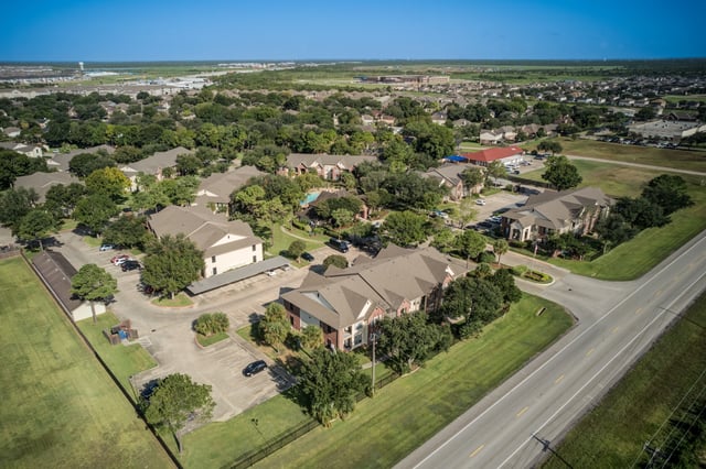 Aerial view of apartment buildings, parking areas, and landscaping.