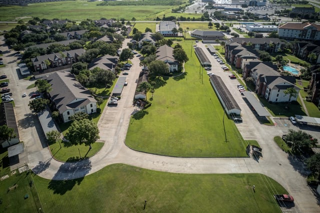 Aerial view of apartment buildings, parking lots, and green spaces.