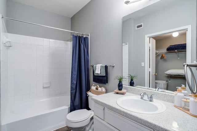 A modern bathroom with a bathtub, toilet, and vanity with a sink.