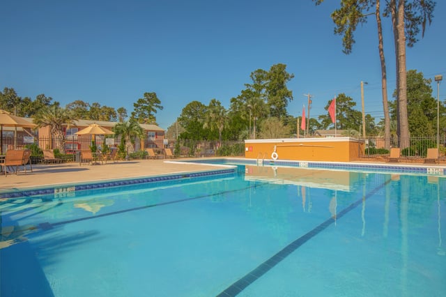 Outdoor swimming pool with lounge chairs and umbrellas.