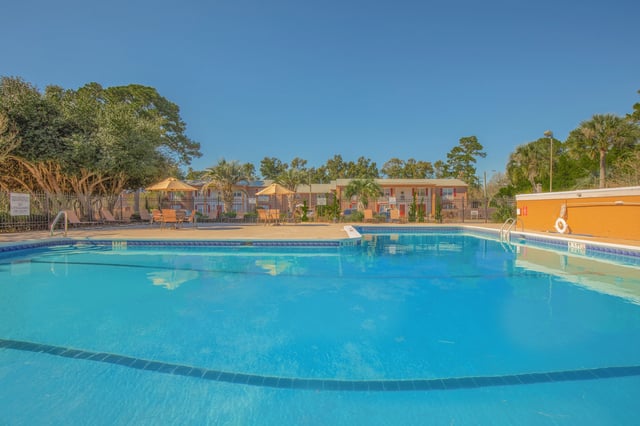 Community pool with lounge chairs and umbrellas.