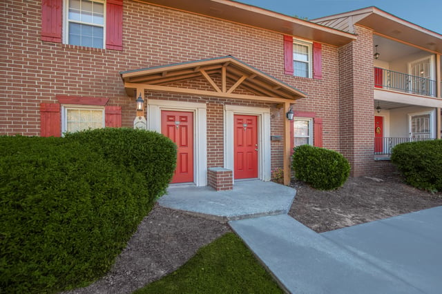 Building exterior with two red doors and shutters.