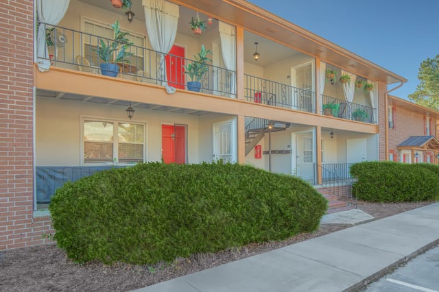 Exterior view of a multifamily apartment building with brick accents and red doors.